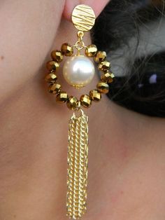 a close up of a woman's face wearing gold earrings with pearls and beads