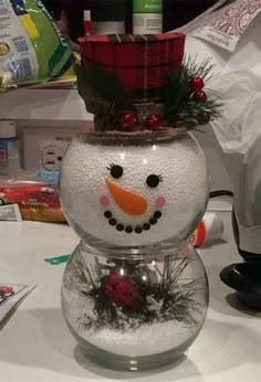 a snowman with a hat on top of it's head sitting in a glass bowl