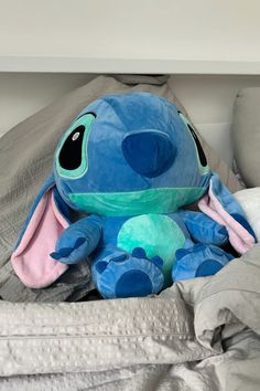 a blue stuffed animal sitting on top of a bed