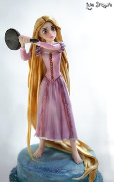 there is a figurine on top of a cake with long blonde hair holding a frying pan