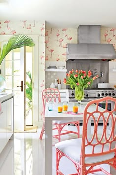 a kitchen with flamingos painted on the walls and chairs around it, including an island