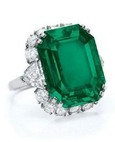 an emerald and diamond ring on a white background