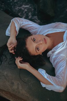 a woman laying on the ground with her hands behind her head and looking at the camera