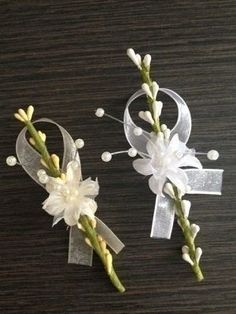 two white flowers are sitting next to each other on a table with ribbons and bows