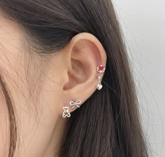 a close up of a person's ear wearing an ear cuff with two hearts on it