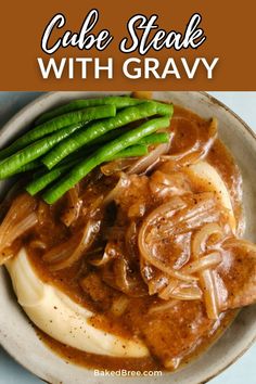 a white plate topped with meat covered in gravy and green beans