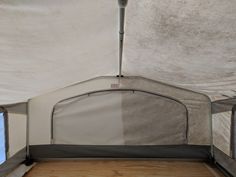 the inside of a tent with wood flooring and white canvas coverings on it