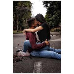 two people sitting on the ground with their arms around each other and one person kissing