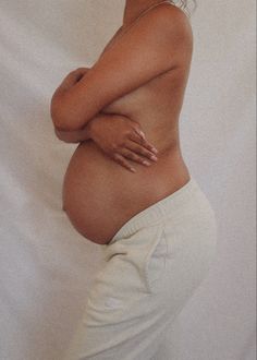 a pregnant woman with her arms crossed in front of her stomach, posing for the camera