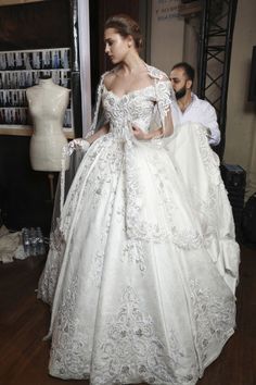 a woman in a white wedding dress standing next to a mannequin