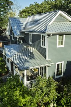 an aerial view of a house with metal roofing and white trim on the windows