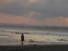 a person walking on the beach at sunset