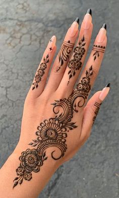 a woman's hand with henna tattoos on her left hand and black nail polish