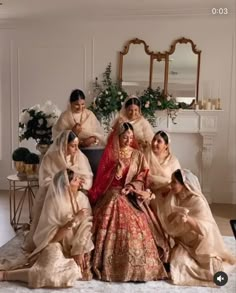 a group of women sitting next to each other on top of a rug in front of a fireplace