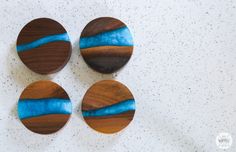 three wooden discs with blue and brown designs on them sitting on a white counter top