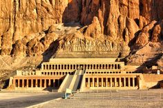 an ancient building in the desert with mountains behind it