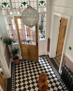 an entryway with a black and white checkered floor, chandelier and wooden door