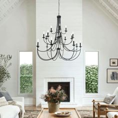 a living room filled with furniture and a chandelier hanging from the ceiling over a fire place