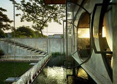 an outdoor area with water and steps leading up to the top floor, in front of a concrete wall