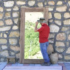 a man standing in front of a stone wall with a large mirror on it's side