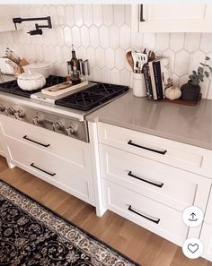 a kitchen with white cabinets and stainless steel stove top, black rug on the floor