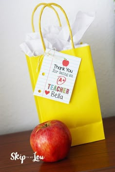 an apple sitting on top of a wooden table next to a yellow paper bag with thank you written on it