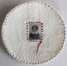 a white plate with a red thread on it and a photo in the center that has been stitched together