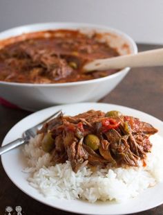 a white plate topped with rice and meat next to a bowl filled with chili sauce