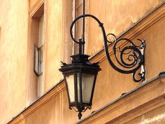 an old fashioned street light hanging from the side of a building