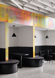 an empty restaurant with black tables and stools in front of colorful wall paper on the walls