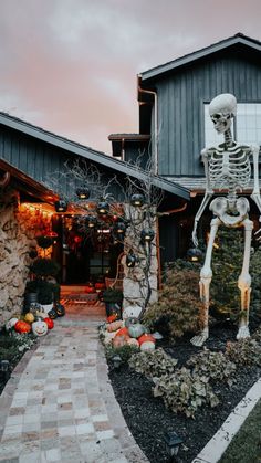 a skeleton statue in front of a house decorated with pumpkins and other halloween decorations