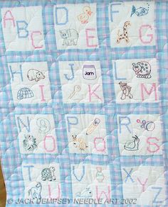 a blue and white checkered quilt with alphabets on the front, along with pictures of animals