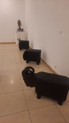 three black couches sitting on the floor in a room with white walls and tiled floors