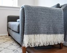 a couch with a blanket on top of it in front of a window and rug