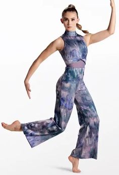 a woman is dancing with her arms in the air while wearing purple and blue pants