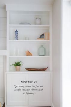 a white book shelf filled with books and vases