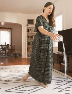 a woman in a long dress is playing with a water spout