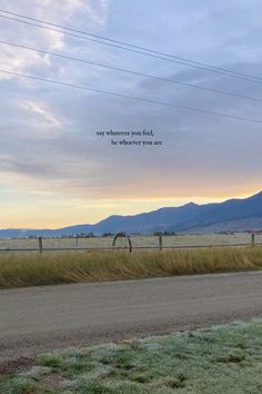 an empty road in the middle of nowhere with mountains in the background and a sky filled with clouds