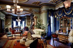 a living room filled with lots of furniture next to a window covered in blue drapes