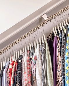 an organized closet with clothes hanging on hooks