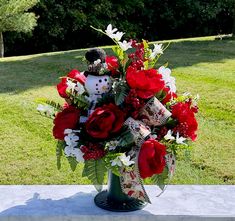 a vase filled with red and white flowers on top of a cement slab in the grass