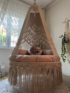 a hammock chair with pillows on it in front of a window