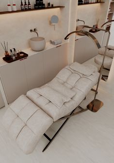 a white reclining chair sitting in front of a shelf filled with bottles and other items