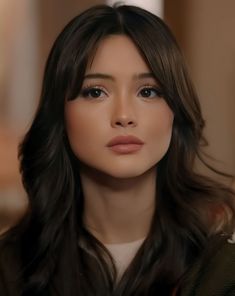 a woman with long dark hair and brown eyes looks at the camera while wearing a black jacket