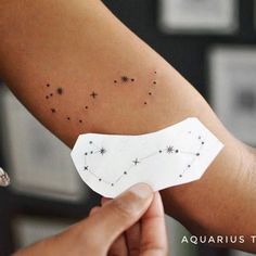 someone is holding up a piece of paper with stars on it and the word aquarius written in black ink