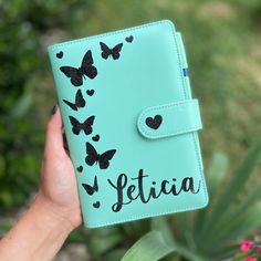 a hand holding a personalized notebook with butterflies on it