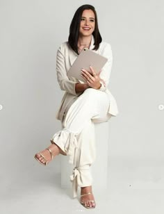 a woman sitting on top of a white chair holding a piece of paper in her hands