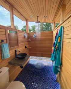 a bathroom with wooden walls and blue tile on the floor, along with a black sink