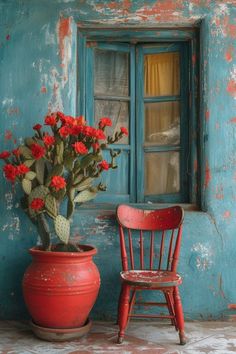 a red chair sitting next to a potted plant in front of a blue wall