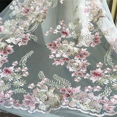 an embroidered fabric with pink flowers and leaves on grey background, closeup view from above